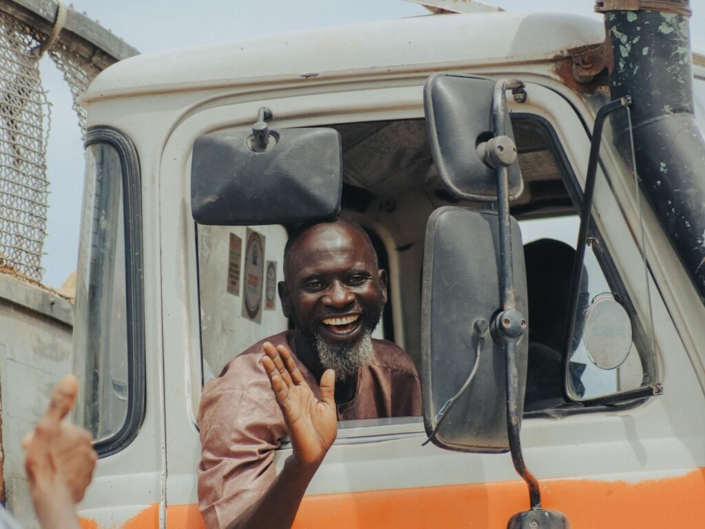 Camionero sonriendo y saludando desde la ventana de su camión